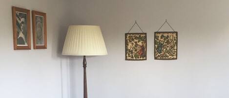 A dining area with a wooden table and chairs, a lamp, and two framed pictures on the wall.