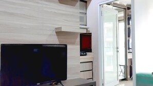 Una sala de estar moderna con un televisor de pantalla plana, estanterías empotradas y un ventanal corredero que da a un balcón.