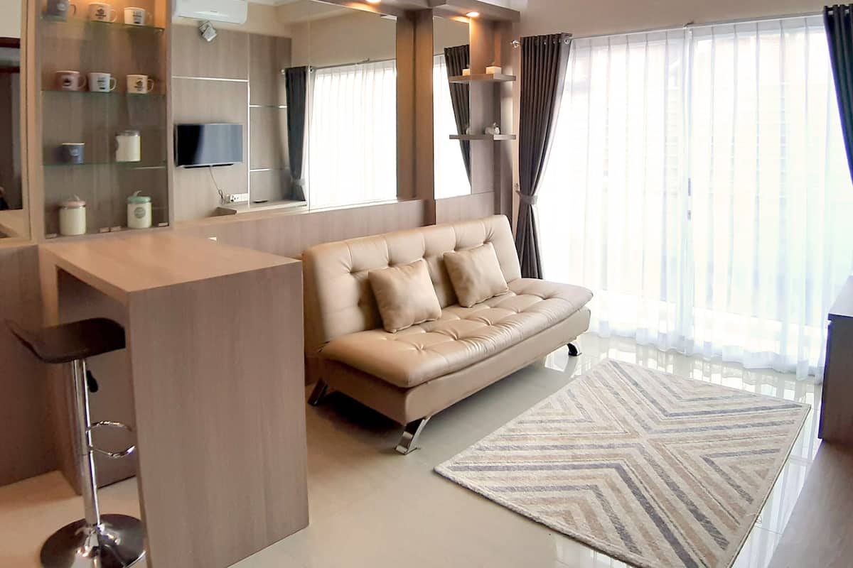 A modern living room with a sofa, a coffee table, a TV, and a large window with curtains.