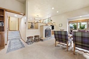 A spacious living room with a fireplace, a staircase, and a view of the outdoors.
