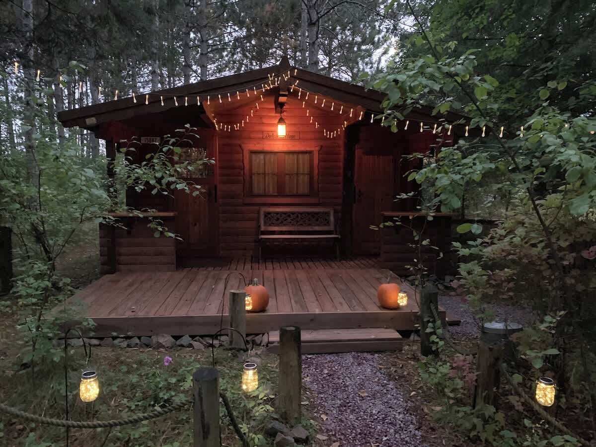 Eine rustikale Holzhütte mit einer Holzterrasse, Lichterketten und Laternen.