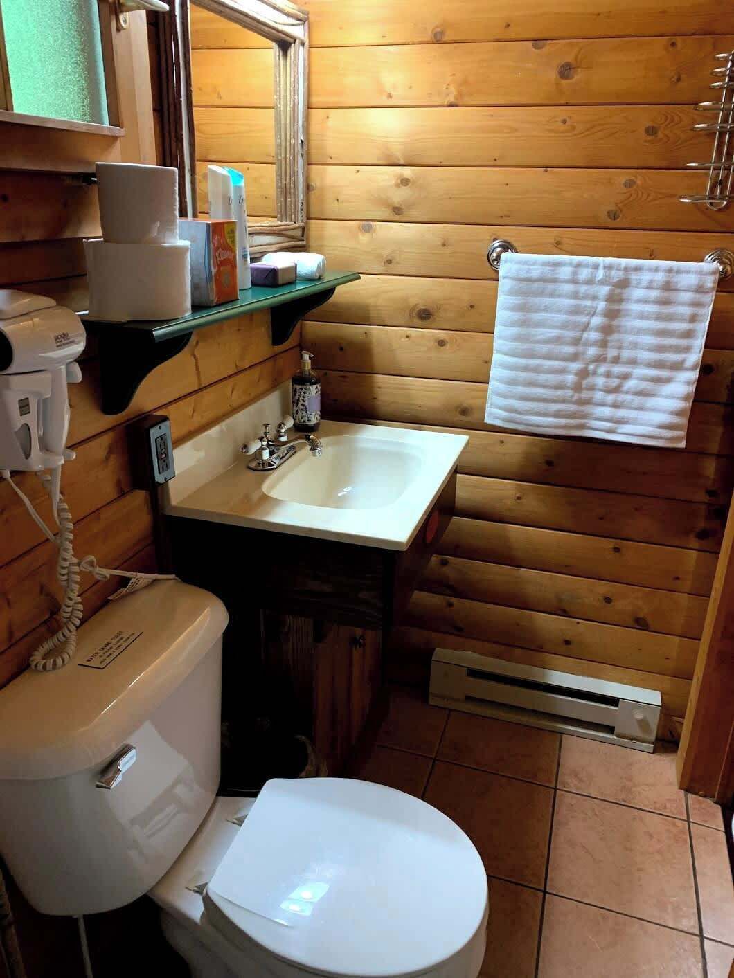 Un baño pequeño con inodoro, lavamanos y una toalla colgada en un perchero.
