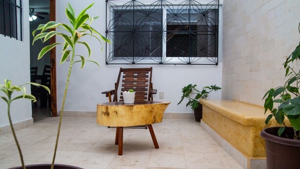 A small, enclosed patio area with a wooden chair, a small table, and several potted plants. - Family bungalow near the sea (Centro)