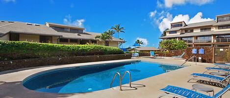A swimming pool with lounge chairs and a stone wall.