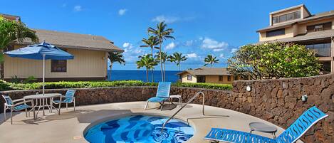 A pool area with lounge chairs, a table, and a blue umbrella.