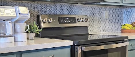 Una cocina con armarios azules, un microondas, una cafetera y un horno.