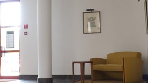 A room with a yellow sofa, a small wooden table, and a framed picture on the wall.