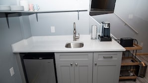 Una cocina compacta con un lavamanos de acero inoxidable, una cafetera y un lavavajillas.