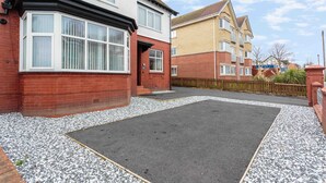 A residential area with a paved driveway and a small garden area with gravel. - Cherry Property - Blueberry Suite (Blackpool)