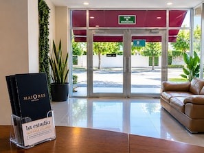 En hotelindgang med receptionsdisk, skilt til nødudgang og udsigt til gaden.
