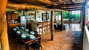 Una cocina rústica con comedor, vigas de madera y vistas al verdor.