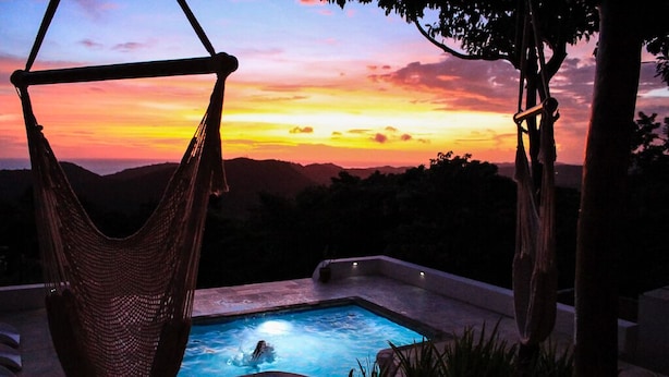 Una hamaca con vista a una piscina al atardecer.