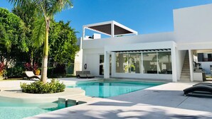Une maison moderne dotée d’une piscine, d’un patio couvert et d’un escalier menant à un étage supérieur.
