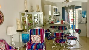Un salon comprenant un canapé, des fauteuils, une table basse et un coin repas avec des chaises et une table.