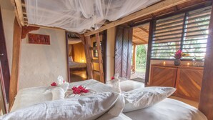 A room with a bed, white linens, a wooden door, and a window with a view of greenery. - Totoco Eco Resort (Altagracia)