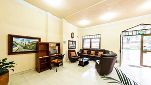 A hotel lobby with a sofa set, a desk with a computer, a bookshelf, and a large framed picture on the wall. - Hotel Valle de Pubenza (Popayán)