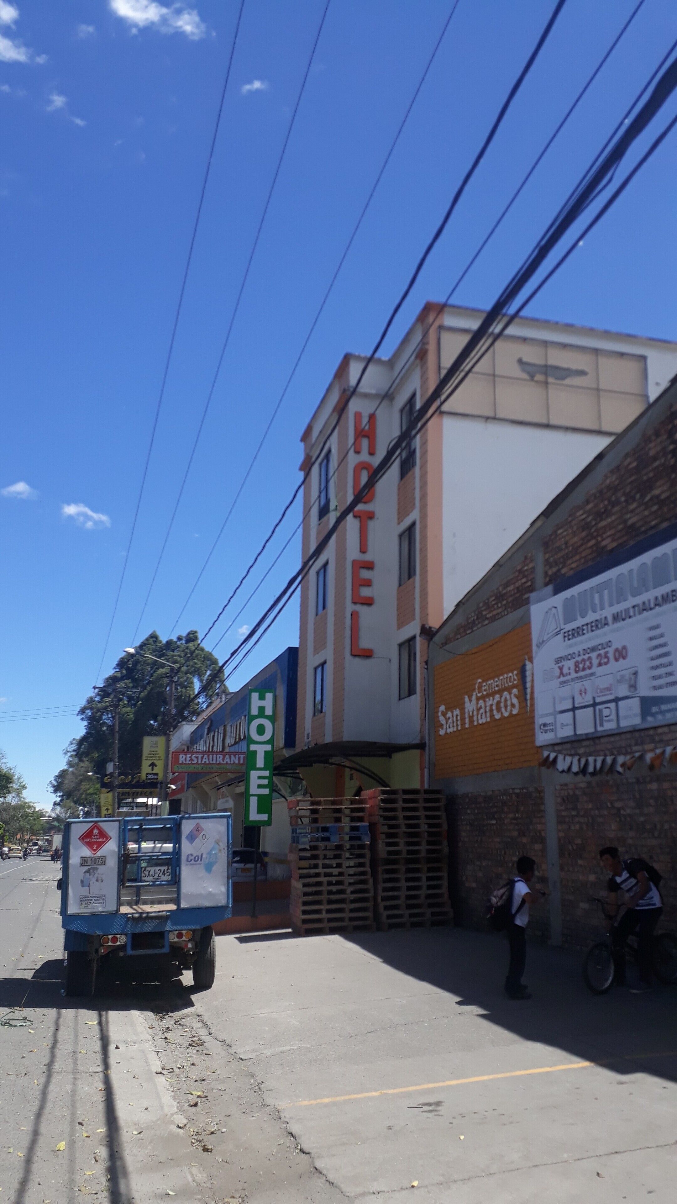 A hotel with a sign reading "HOTEL" and a building with a sign for "San Marcos Cementos".