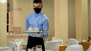 A waiter in a blue shirt and black apron carrying a tray with two white cups and a plate. - Hotel Valle de Pubenza (Popayán)