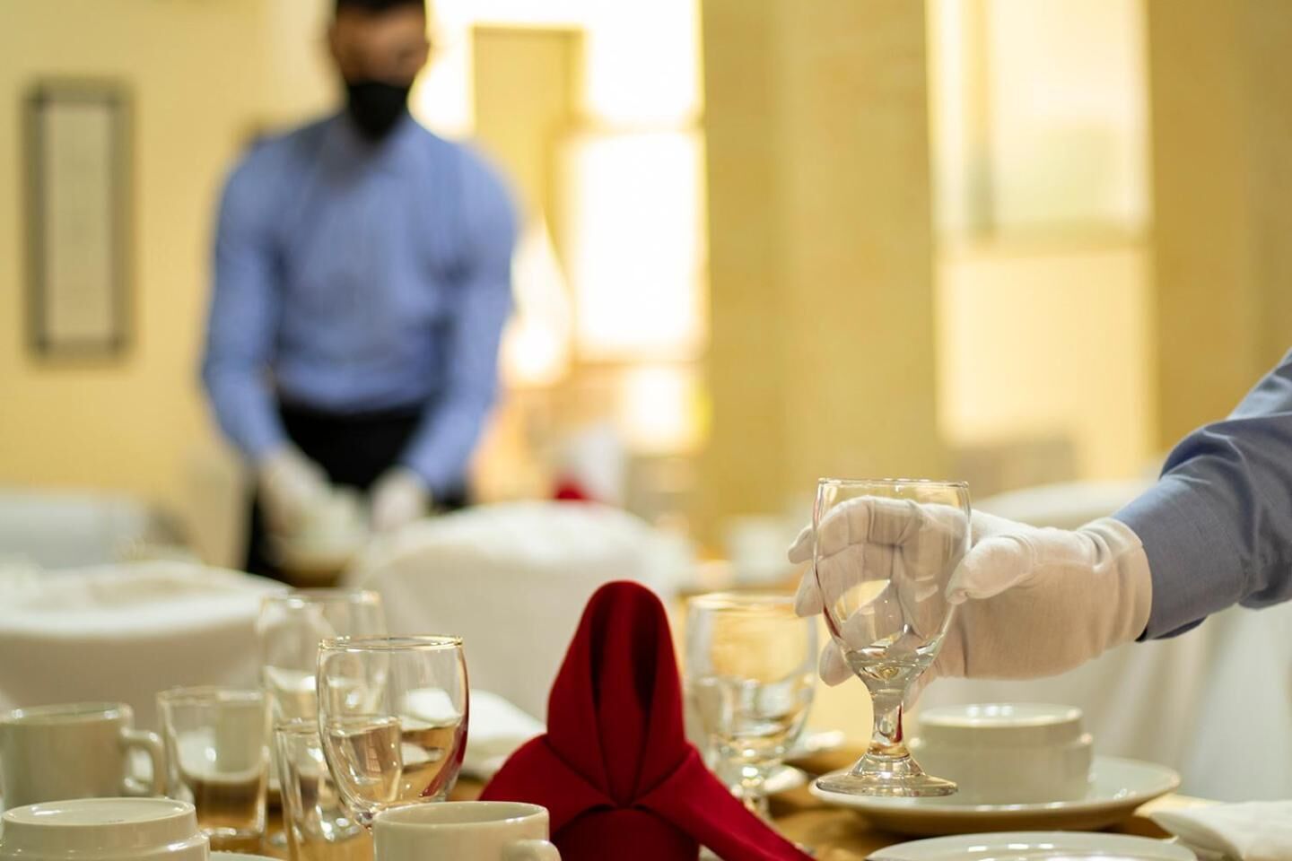A dining table with various glassware and a red napkin, suggesting a formal dining setting.