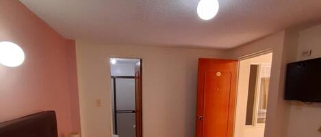 A bedroom with a bed, a TV, and a door.