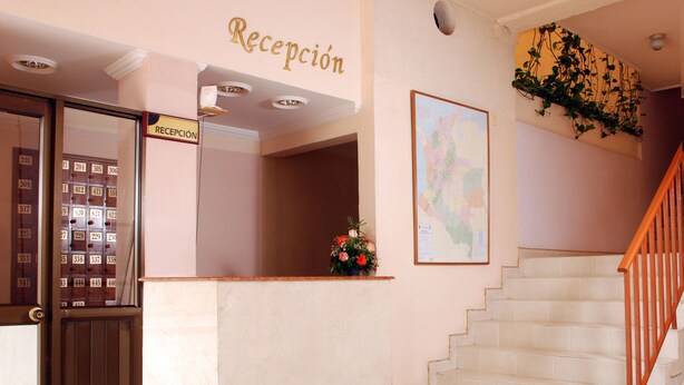 A reception area with a reception desk, a staircase, and a wall-mounted map. - Hotel Valle de Pubenza (Popayán)