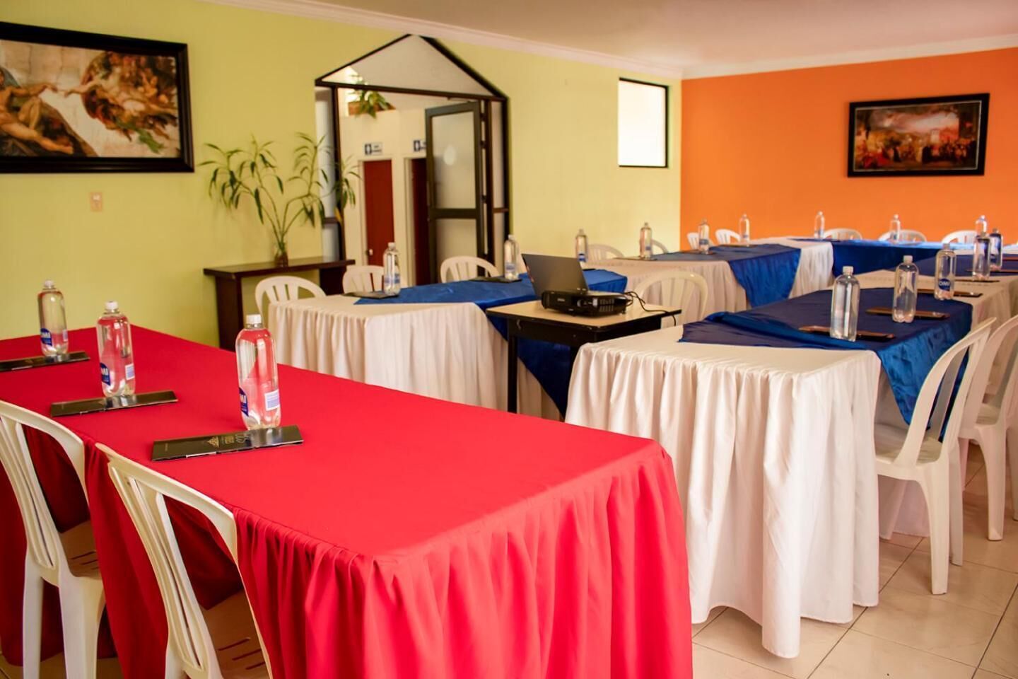 A conference room with tables set for meetings, equipped with laptops and water bottles.