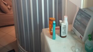 A bathroom with a striped shower curtain, a white cabinet, and toiletries on the counter. - Open space apartment (Cecina)