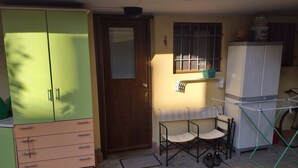 A compact room with a wooden door, a small table with chairs, a drying rack, and a white cabinet. - Open space apartment (Cecina)