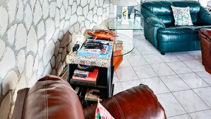 Een woonkamer met stenen muren, een leren bank, een glazen salontafel en een houten plafond.