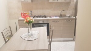 A modern kitchen with a dining table, chairs, a vase with flowers, and a gas stove.