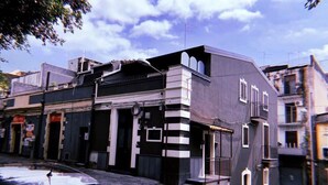 A building with a unique architectural design, featuring a combination of black and white panels, a central entrance with steps, and a small balcony.