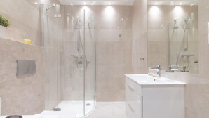 Une salle de bain moderne avec une douche à parois de verre, un meuble-lavabo blanc avec un miroir et des toilettes.