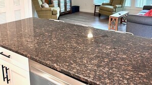 A modern kitchen with granite countertops, a built-in dishwasher, and a dining area with a table and chairs. - 122 Falkirk Small Pet Friendly Cottage near Beach (Fort Myers Beach)