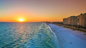 A beach with a sunset, a hotel, and a clear sky. - Full Ocean Views, Steps to the Sand, Beach Chairs, Heated Pool/Hot Tub, Sleeps 8 (Miramar Beach)