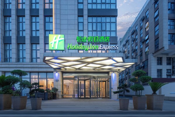Entrada d'un hotel Holiday Inn Express amb un disseny modern, que destaca una porta giratòria de vidre i plantes en testos.