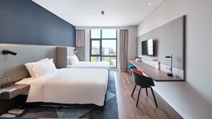 A modern hotel room with two beds, a desk, a chair, and a large window offering a city view.