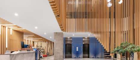 Un moderno vestíbulo de hotel con una mesa de recepción, ascensores y una escalera.