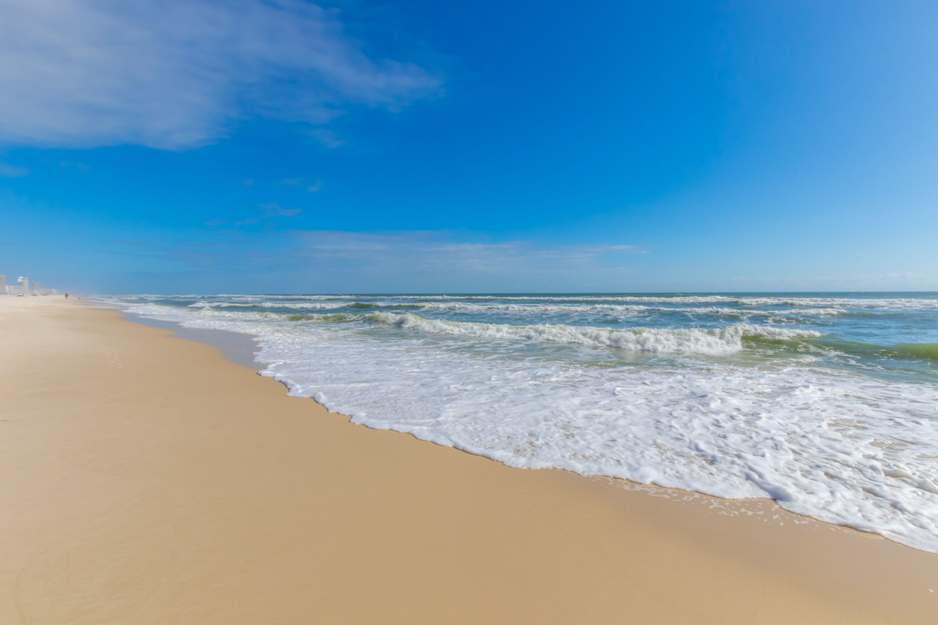 A beach with a clear sky and waves.