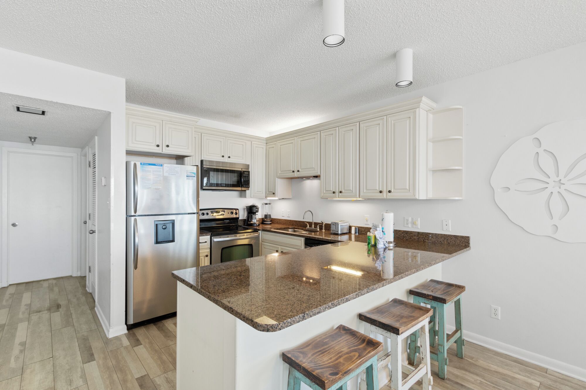A modern kitchen with white cabinetry, stainless steel appliances, and a granite countertop.