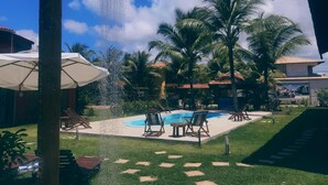 Un área de piscina con fuente de agua, palmeras y sillas de descanso.