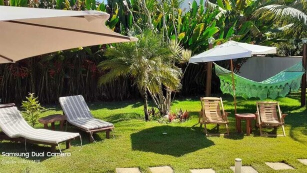 Un jardín con sillones de jardín, sombrillas y una hamaca.