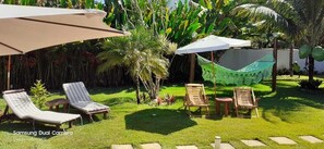 A garden with lounge chairs, umbrellas, and a hammock. - Pousada Pérola da Barra (Maraú)