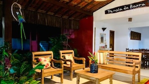 Un banco y sillas de madera en una habitación con techo de paja y un letrero que dice "Perola da Barra".
