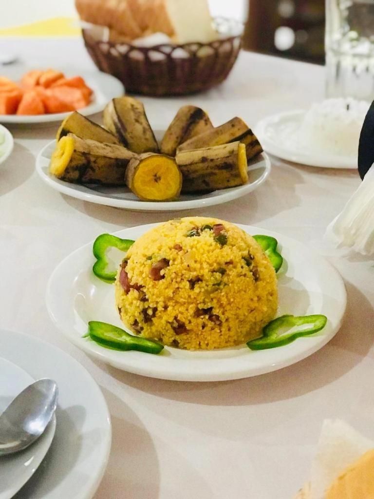 A dining table with plates of food, including a yellow rice dish and sliced vegetables.