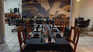 A dining area with a long table set for a meal, surrounded by chairs.