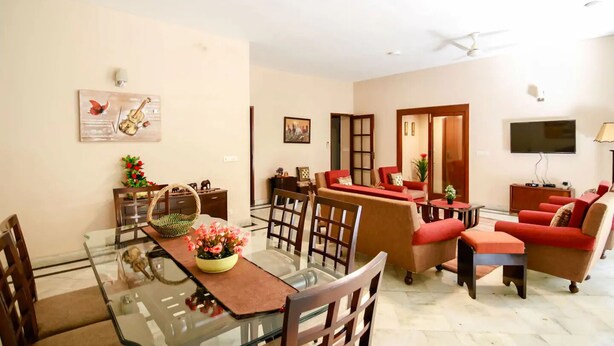 Una sala de estar moderna con una mesa de comedor de vidrio, sofás rojos y un televisor de pantalla plana.