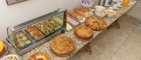 Un bufé con diversas opciones de panadería, incluyendo pasteles, tartas y una tarta grande.