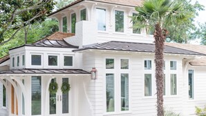 A two-story house with a covered porch, large windows, and a palm tree. - Elegant Cottage on the Bluff Downtown Fairhope (A) (Fairhope)