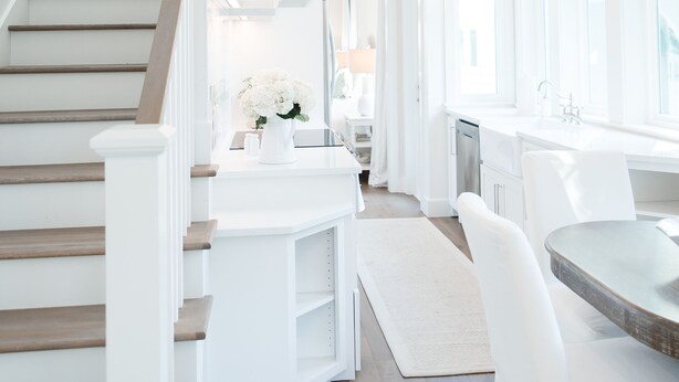 A modern kitchen with white cabinetry, a wooden staircase, and pendant lighting. - Elegant Cottage on the Bluff Downtown Fairhope (A) (Fairhope)