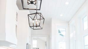 A modern kitchen with stainless steel appliances, white cabinetry, and a geometric pendant light. - Elegant Cottage on the Bluff Downtown Fairhope (A) (Fairhope)